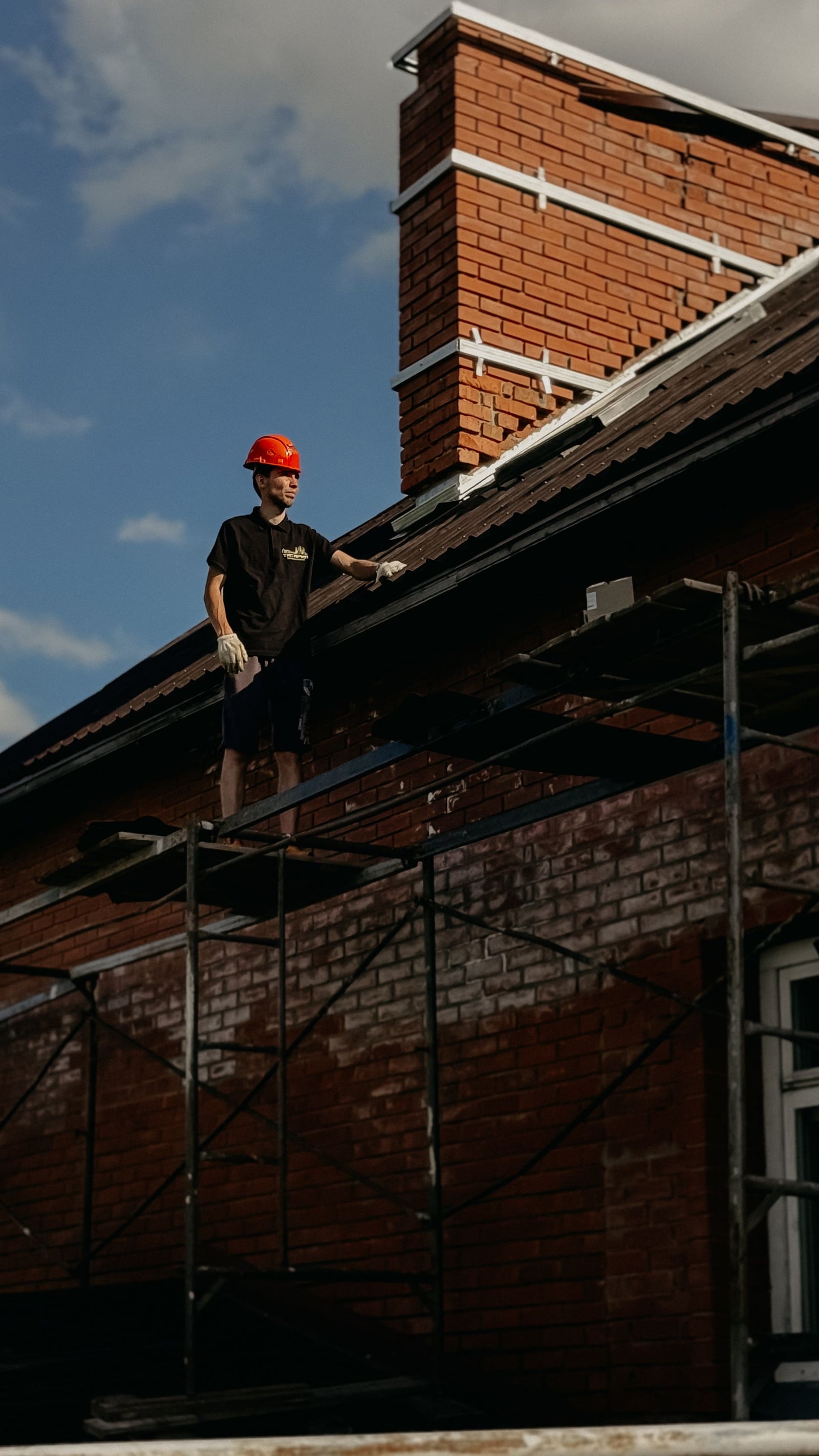 Roofer working near a brick chimney where counter flashing is installed