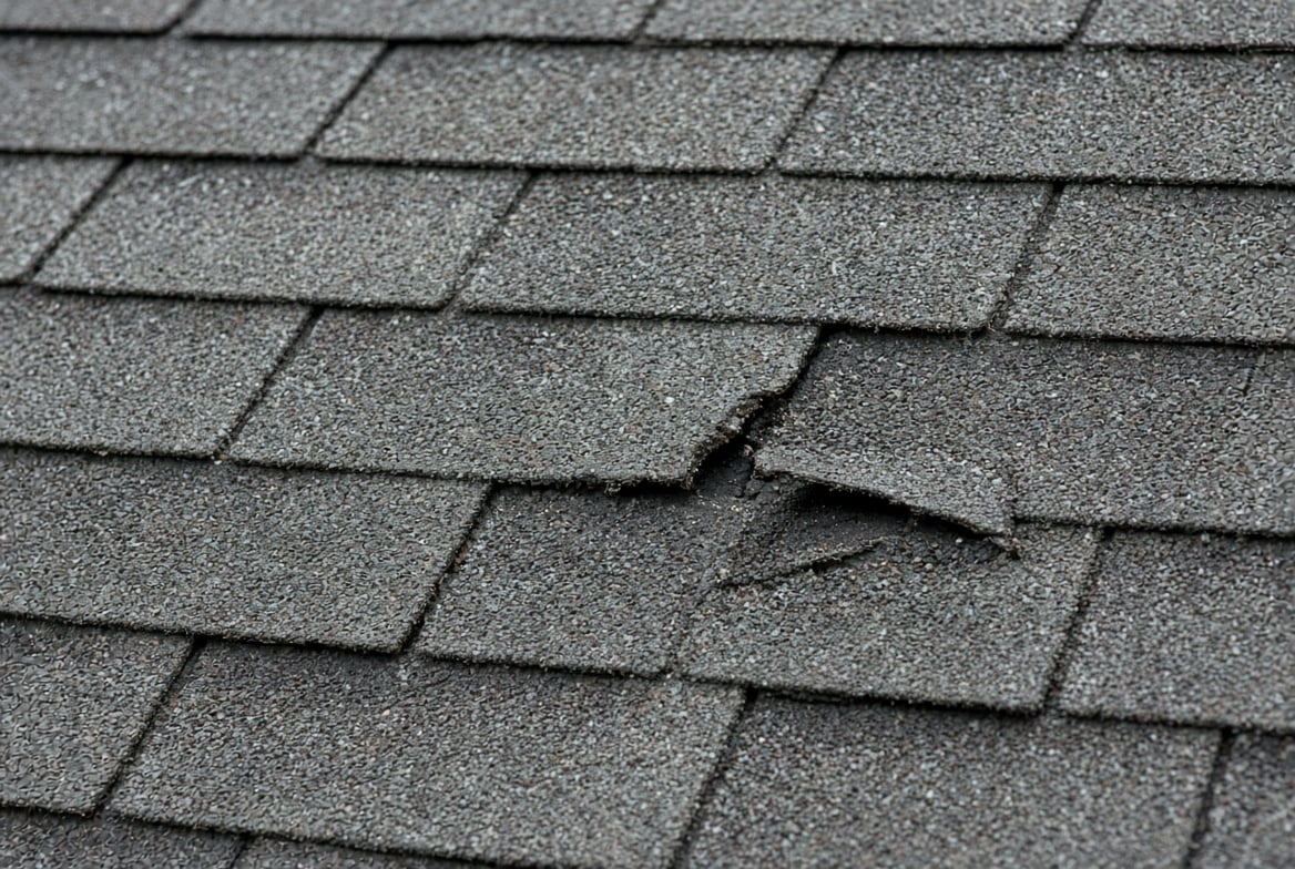 Close up of weathered flat composition 3-tab shingles with a cracked tab