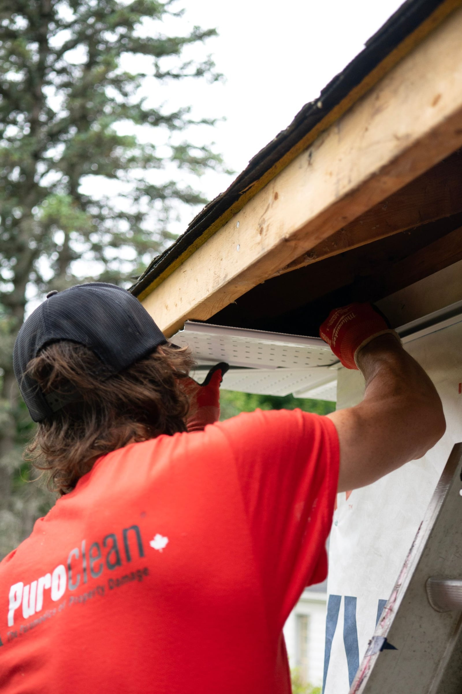 Person clearing debris from a gutter