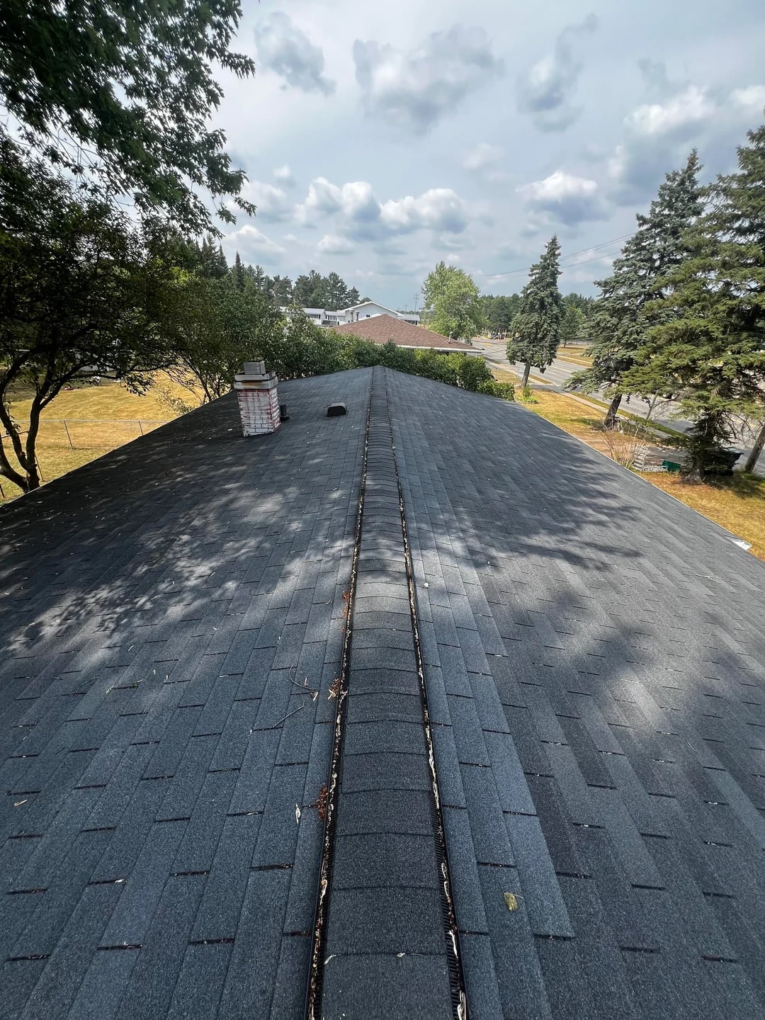 Ridge cap shingles and roof ventilation along the peak of a Huntington Beach roof