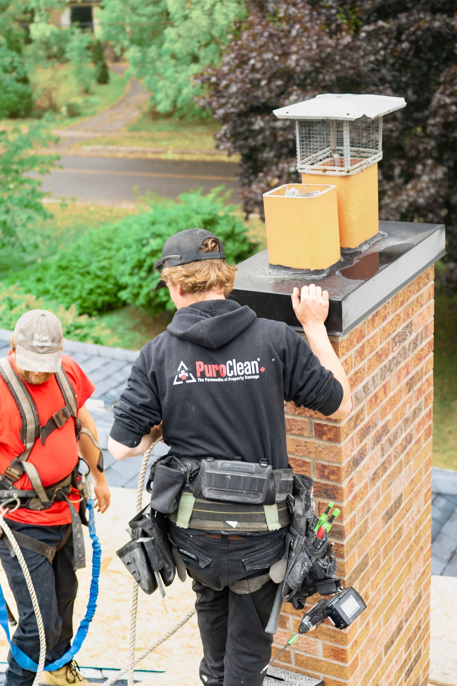 Roofing workers inspecting near a chimney on a rooftop