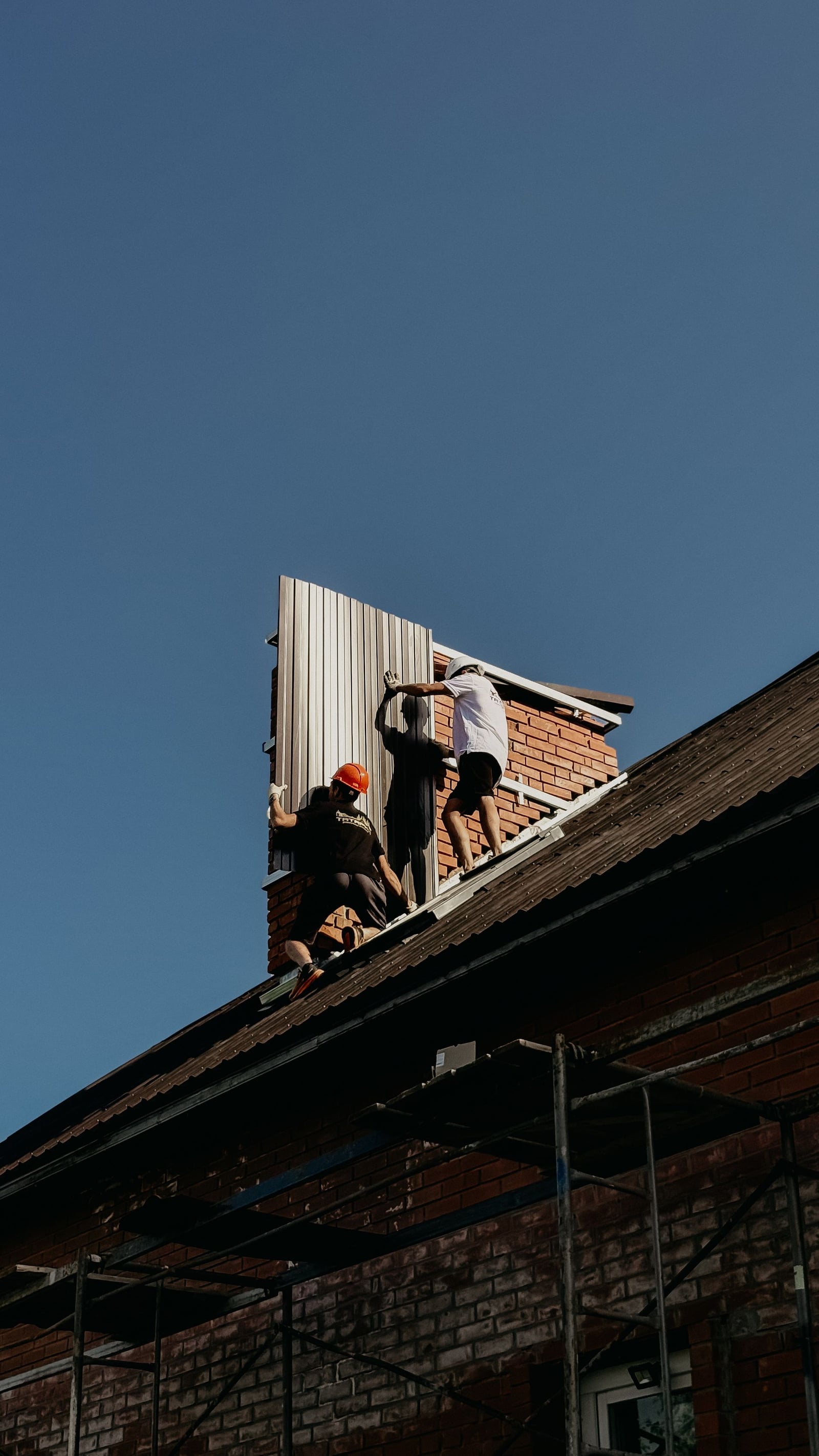 Roofer installing metal flashing along a roof edge