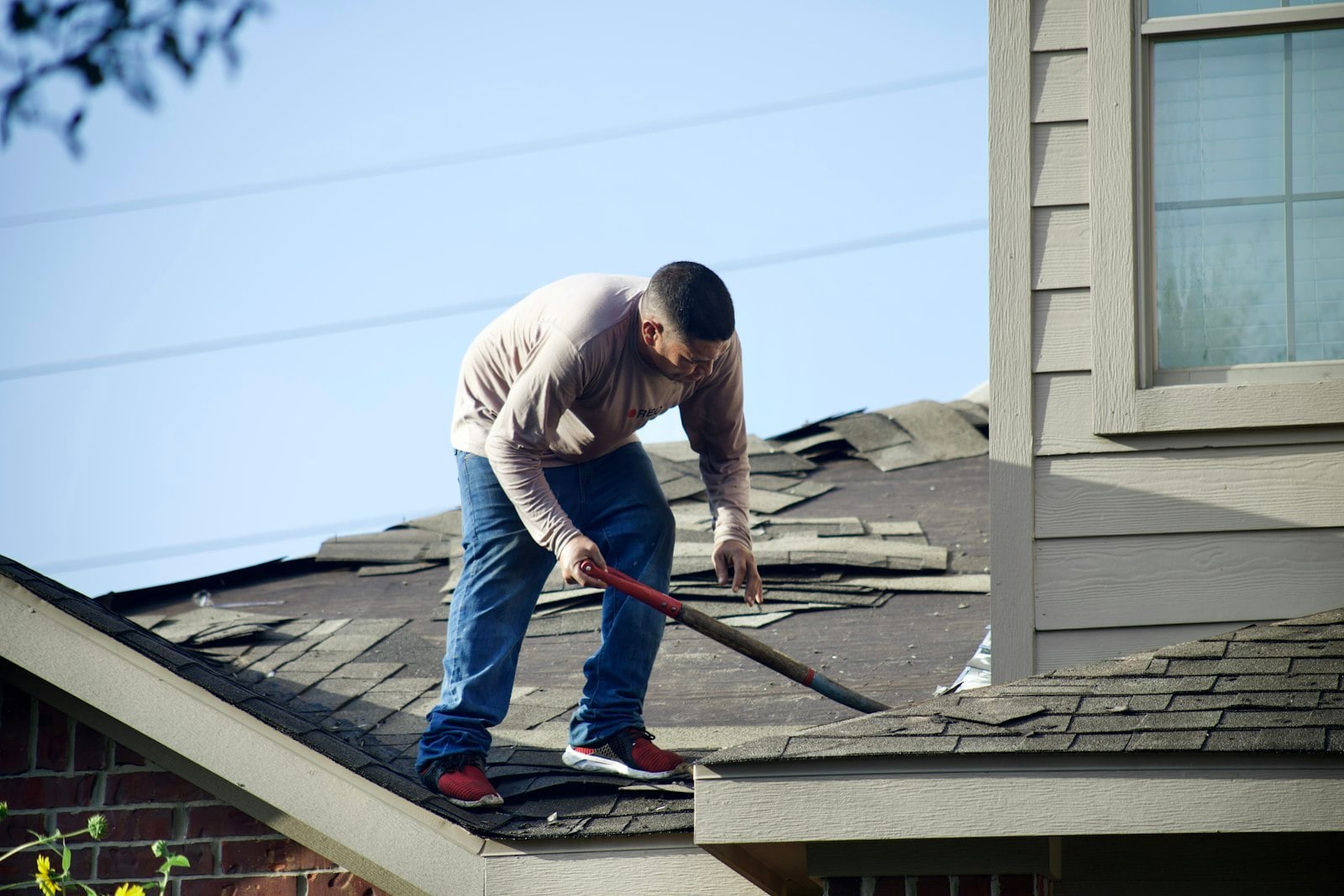 Roofer assessing a Huntington Beach roof before writing up a repair estimate