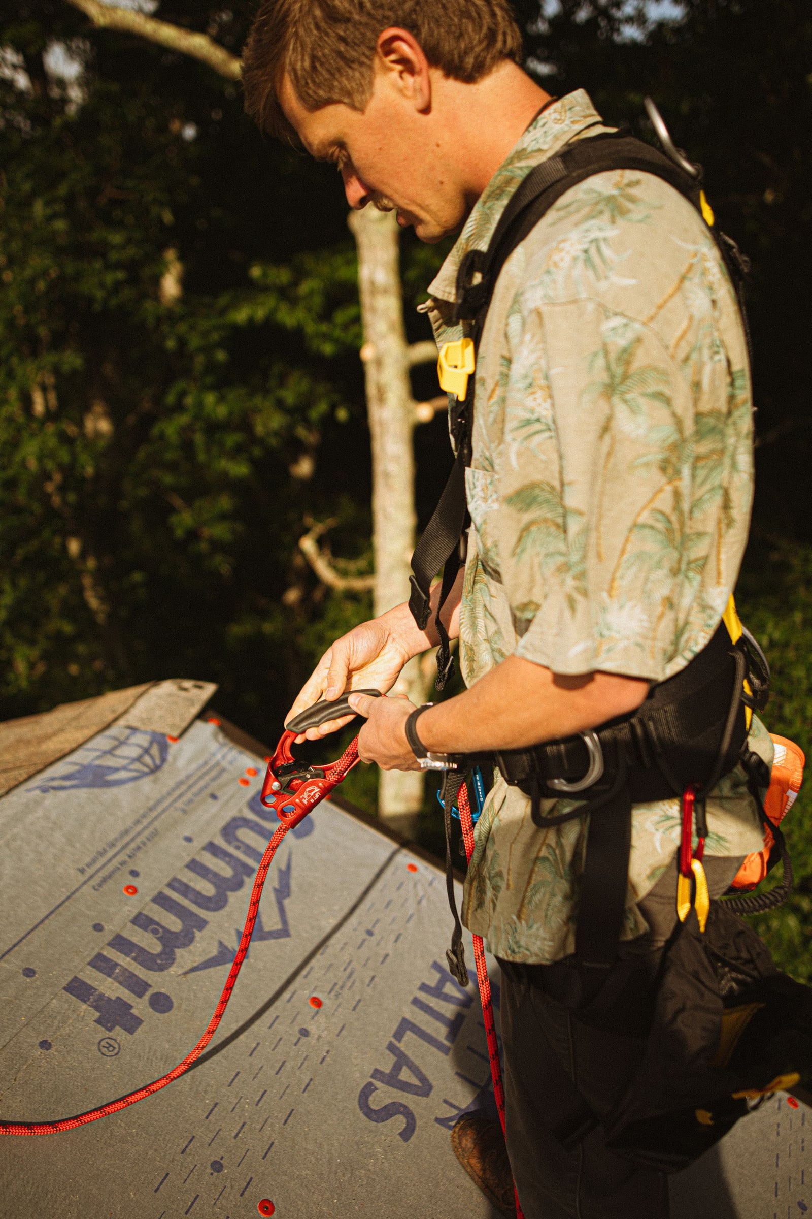 Roofer wearing a safety harness while working on a sloped roof