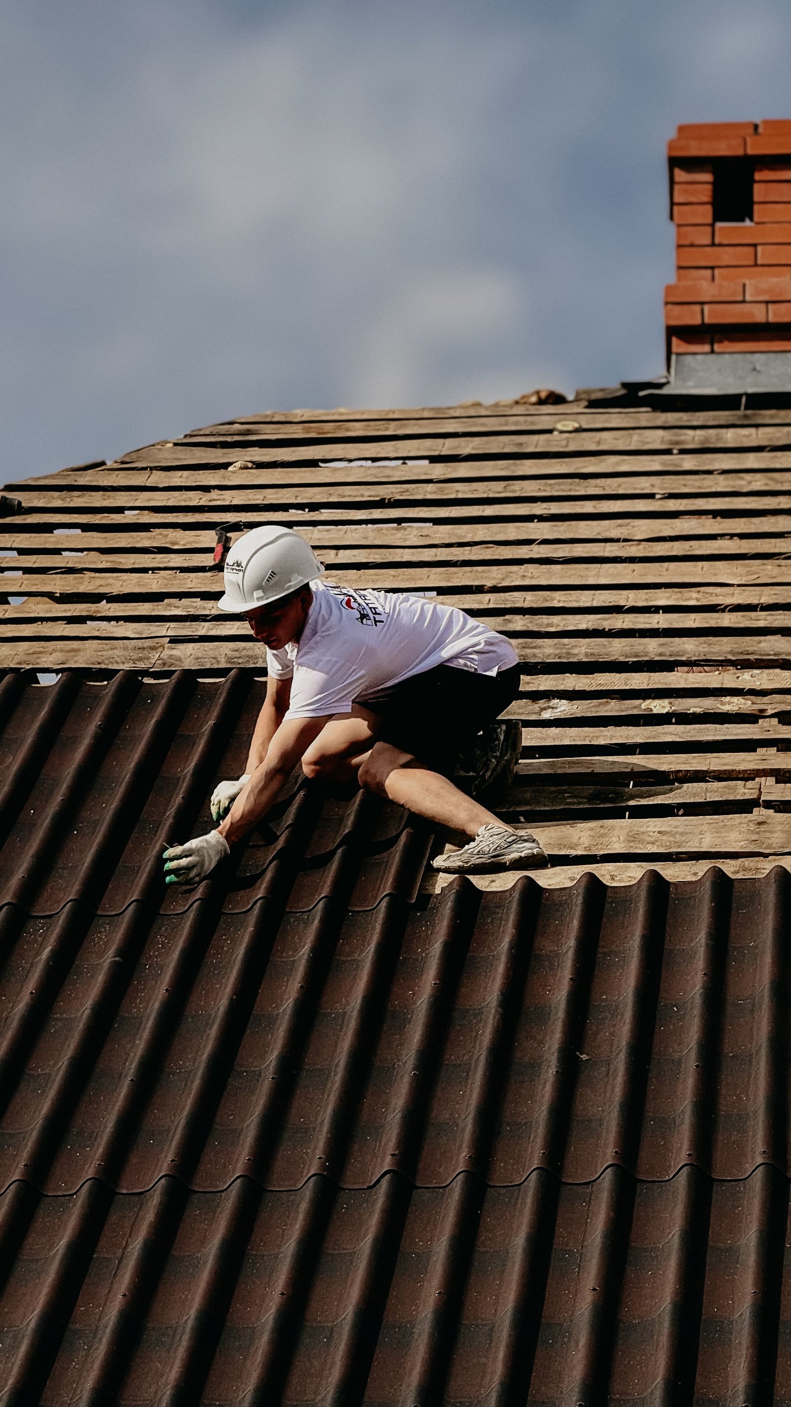 Roofer inspecting a tile roof valley near a chimney