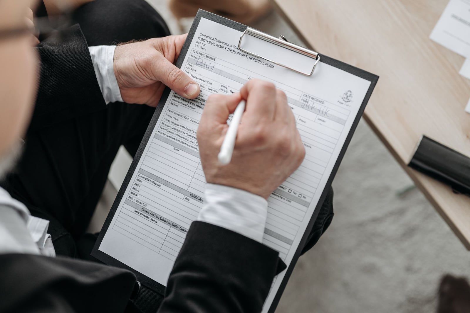 Person signing a formal document on a clipboard