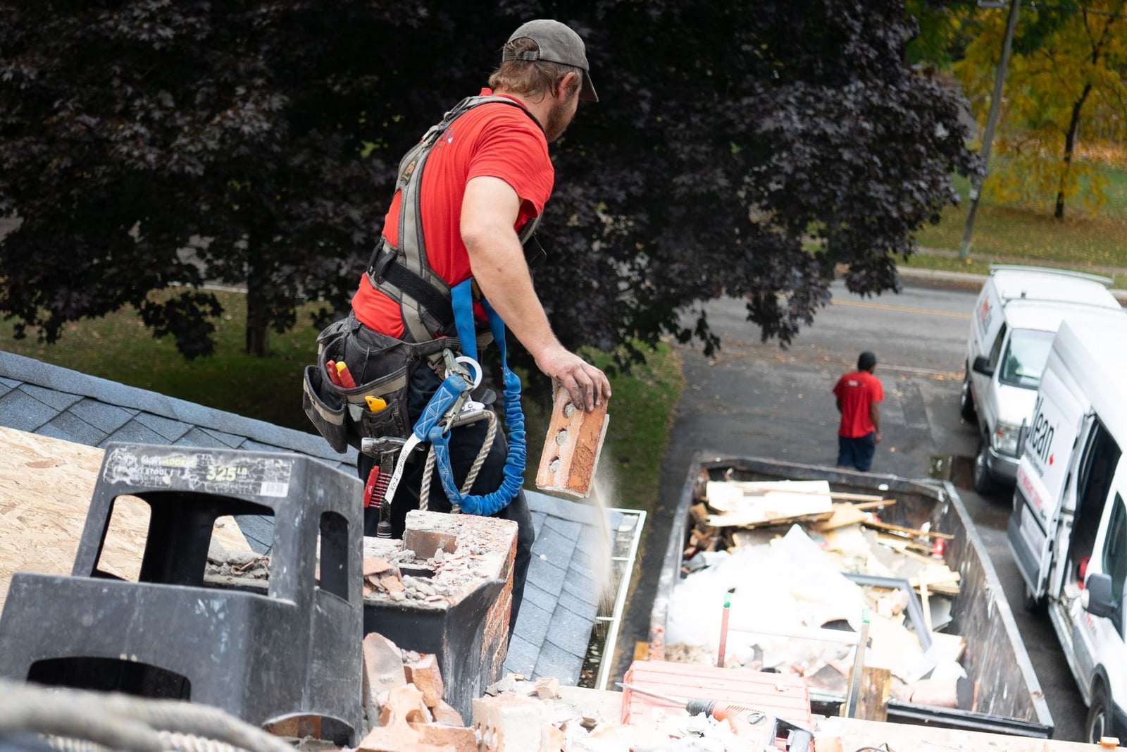 Worker removing old roofing debris during a tear-off